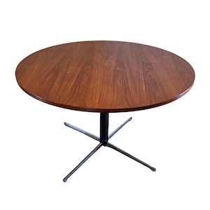 May include: A round, mid-century modern table with a dark wood grain top and a black and silver metal base. The table is approximately 30 inches in diameter and stands on a four-legged base.