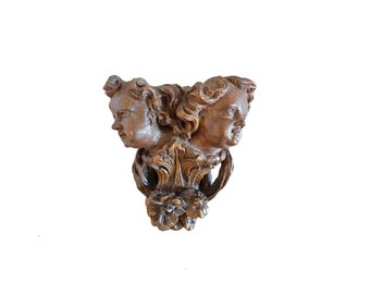 May include: A carved wooden wall bracket with two cherub faces and ornate floral details.