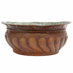 May include: A large, oval copper planter with a wavy, embossed design. The planter has a green patina and a slightly flared rim.