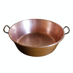 May include: A large copper pot with hammered texture and two brass handles. The pot is empty and has a shiny, reflective surface.