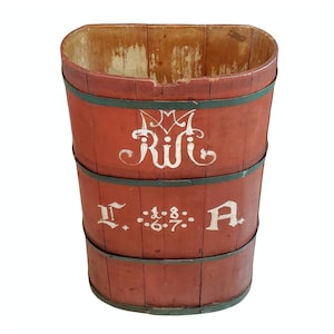 May include: A red wooden bucket with black metal bands and white painted lettering. The lettering reads "R.W.C. 1867 A."