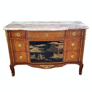 May include: A French antique chest of drawers with a marble top and a black lacquered drawer with a hand-painted Asian scene. The chest has a marquetry design and brass hardware.