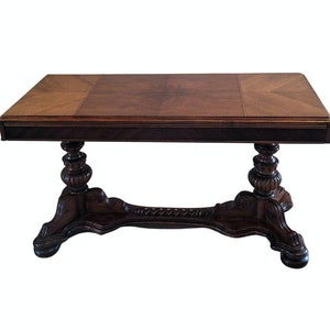 May include: A dark brown wooden table with a rectangular top and a carved base. The table top has a parquet design with alternating light and dark wood.