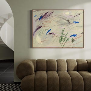 May include: A rectangular framed wall art piece featuring an abstract composition on a light beige background. The artwork displays scattered gestural marks in shades of blue, dark purple, green, and pink, with thin pencil-like lines and brushstrokes.