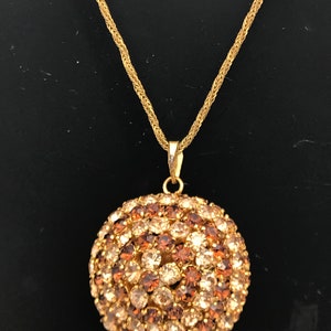 Un inusual collar con colgante de bola de diamantes de imitación en tonos dorados de los años 60 y 70 y grandes pendientes con clip a juego