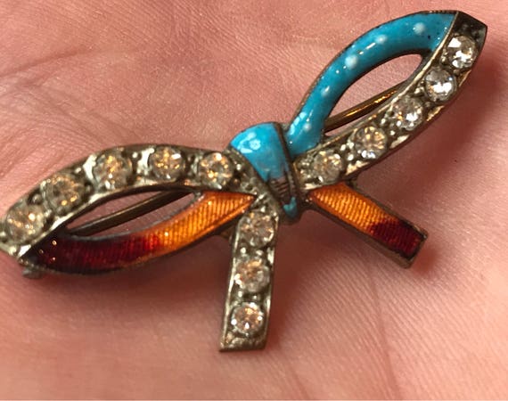A Victorian enameled bow brooch set with old cut crystals.