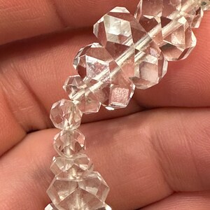 May include: A strand of clear quartz crystal beads, each bead is faceted and has a unique shape. The beads are strung on a silver wire.