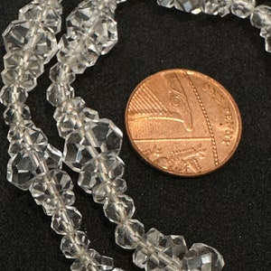 May include: A strand of clear faceted crystal beads, with a British one pence coin for scale.