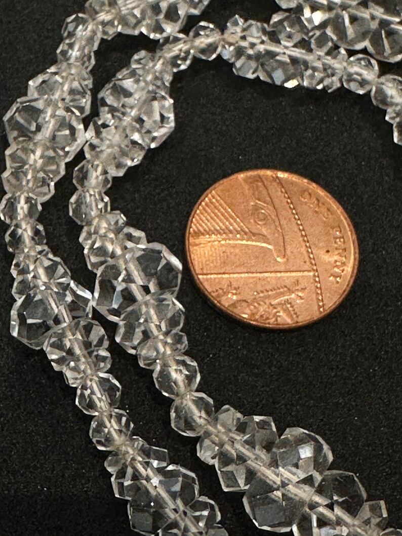 May include: A strand of clear faceted crystal beads, with a British one pence coin for scale.