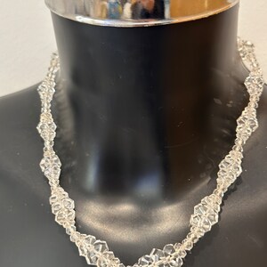 May include: A clear crystal necklace with faceted beads in a flower shape.