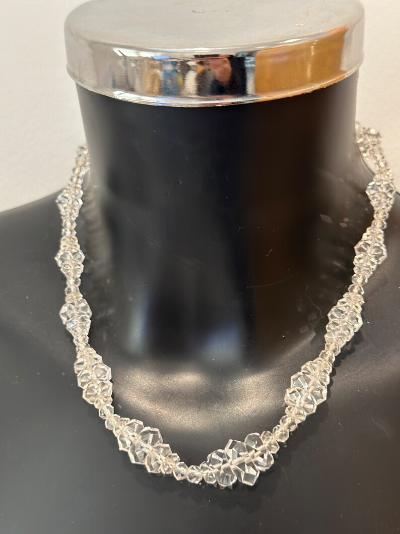 May include: A clear crystal necklace with faceted beads in a flower shape.