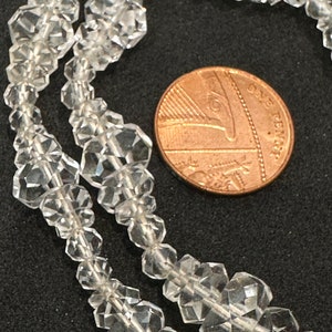 May include: A strand of clear faceted crystal beads, shown next to a British one penny coin for scale.