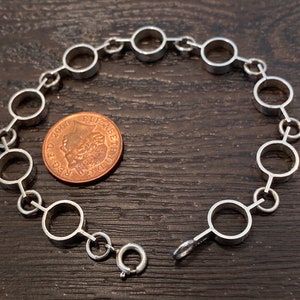 May include: A silver bracelet with a chain of connected circles. The bracelet has a lobster clasp closure.