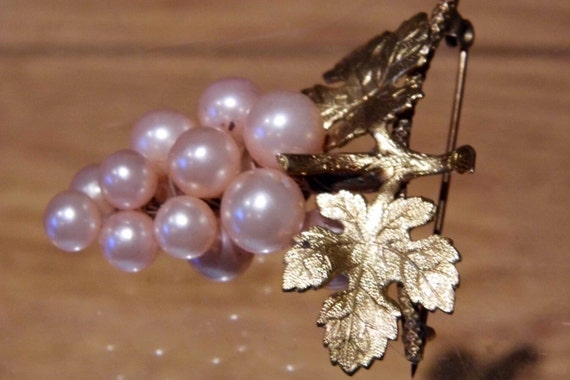 A vintage bunch of grapes brooch in imitation pearl and gold tone metal