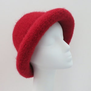 May include: A red fuzzy bucket hat. The hat is made of a soft, fluffy material and has a wide brim.