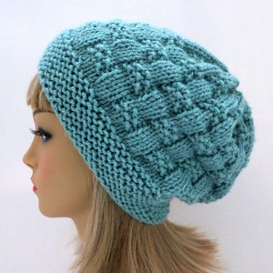 May include: A teal blue knitted beanie with a textured cable knit pattern.