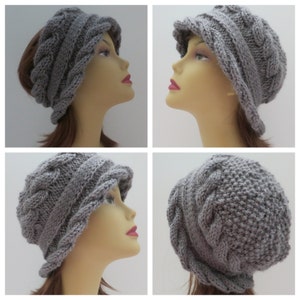 May include: A gray knitted hat with a cable knit design. The hat has a wide brim and is folded down on the sides.