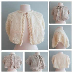 May include: A white knitted bolero with a cable knit design and a button closure. The bolero is shown on a white mannequin. There are also images of the bolero in a beige color.