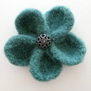 May include: A teal blue felt flower with a silver and black button in the center.