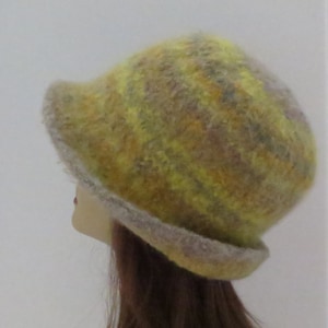 May include: A yellow and gray felted wool hat with a wide brim. The hat is made of a soft, textured material and has a unique, abstract pattern.