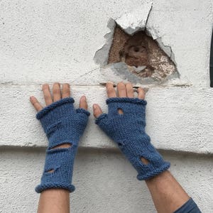 May include: A pair of blue fingerless gloves with holes in the fingers. The gloves are knitted and have a textured surface.