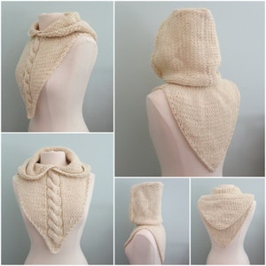 May include: A cream-colored knitted cowl with a hood. The cowl is shown on a white mannequin. The cowl has a cable knit pattern and a triangular shape.