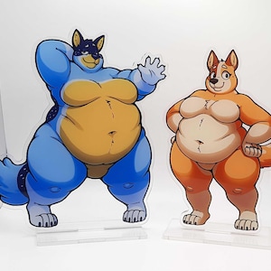 May include: Two cartoon-style acrylic figures of anthropomorphic dogs. One is blue with a yellow belly, the other is orange with a cream belly. Both are standing on clear acrylic bases.