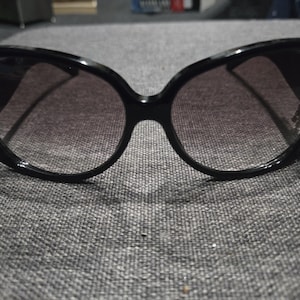 May include: Black cat-eye sunglasses with a dark gray lens.