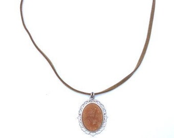 Necklace with silver colored pendant and brown cabochon attached to a brown faux leather cord. Handcrafted vegan collar with faux suede cord