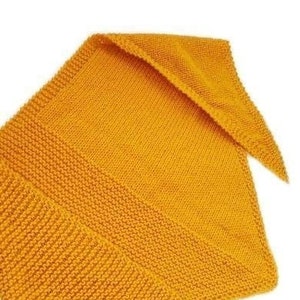 May include: A yellow knitted triangular shawl or scarf. The shawl is made of a soft, textured yarn and has a simple, elegant design.