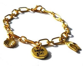 Gold colored bracelet with goldplated metal charms. Multi charm wristlet with gold colored chain links, closure and charms beach, sea, ocean