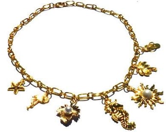 Gold-coloured necklace with goldfilled metal charms. Multi charm necklace with gold colored chain links, closure and charms beach sea summer