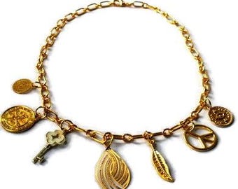 Gold-coloured collar with goldplated metal charms. Multi charm necklace with gold colored chain links, closure, charms, evil eye, coin, key