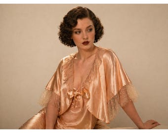 Chaqueta de cama vintage de los años 30, color melocotón pálido, satén de seda, ribete de encaje, lazo de cinta, estilo Art Déco.