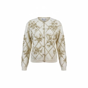 May include: Cream-colored cardigan sweater with gold floral embroidery and diamond pattern. The long-sleeved sweater has a round neckline and button closure. The word "Knitting" is embroidered on the back of the collar.