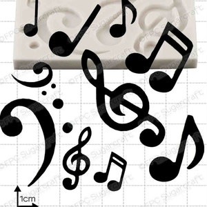 Puede incluir: Un molde de silicona para hornear o hacer decoraciones de fondant. El molde presenta varias notas musicales y una clave de sol. El molde es blanco y mide 1 cm.
