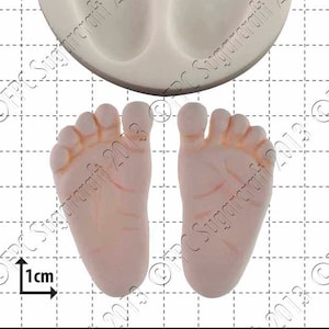 以下が含まれることがあります： 赤ちゃんの足跡を焼くためのシリコンモールド。モールドは白で、つま先のある赤ちゃんの足が2つ表示されています。モールドのサイズは1cmです。