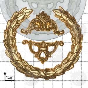 May include: A white silicone mold with a design of a wreath with a decorative flourish in the center. The mold is 1 cm in diameter.