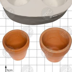 May include: A white silicone mold for making two small terracotta-colored flower pots. The mold is oval-shaped with two round depressions. The mold is shown next to two finished pots, each approximately 1 cm in diameter.
