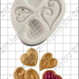 Puede incluir: Molde de silicona con cuatro formas de corazón. El molde es blanco y los corazones tienen varios diseños. Hay cuatro corazones terminados en oro y rojo.