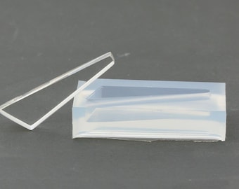 May include: A clear plastic mold with a rectangular shape and a smaller rectangular cutout inside. The mold is sitting on a gray surface next to a clear plastic frame.
