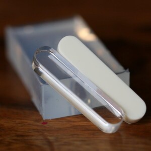 Peut inclure: Deux limes à ongles en verre transparent, dont une avec un revêtement en plastique blanc, sont posées sur une surface en bois.