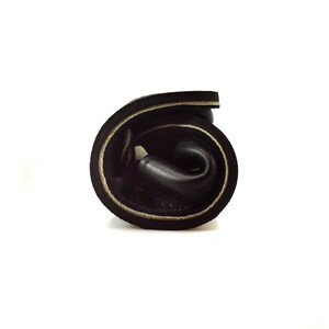 May include: A rolled up black leather strap with white stitching detail.