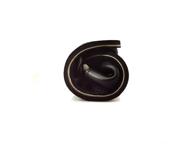 May include: A rolled up black leather strap with white stitching detail.