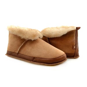 May include: A pair of brown sheepskin slippers with a fold-over cuff and a soft, fluffy lining. The slippers have a leather sole and a comfortable fit.