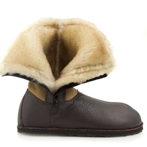 May include: A brown leather boot with a zipper and a fluffy beige lining. The boot is folded down to show the lining.