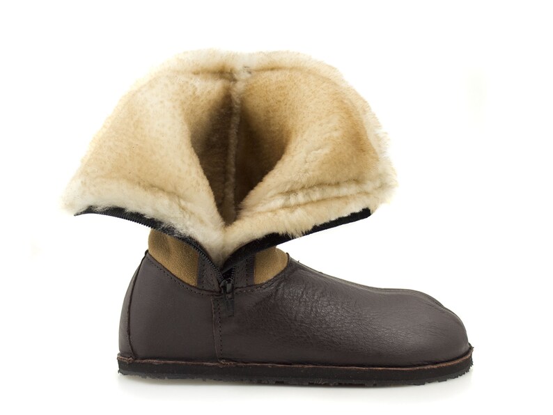 May include: A brown leather boot with a zipper and a fluffy beige lining. The boot is folded down to show the lining.