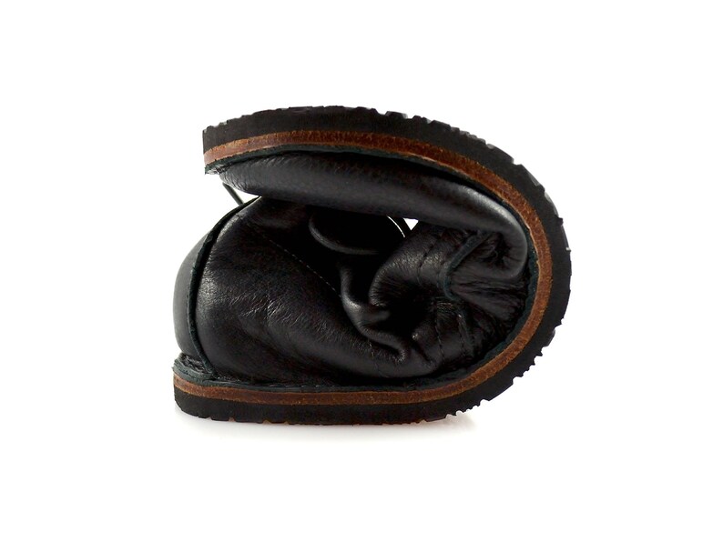Puede incluir: Primer plano del interior de un zapato de cuero negro con suela de cuero marr&oacute;n.