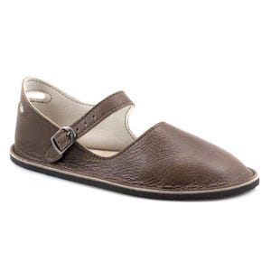 May include: Brown leather flat shoes with a buckle strap and a closed toe. The shoes have a simple design and a comfortable look.
