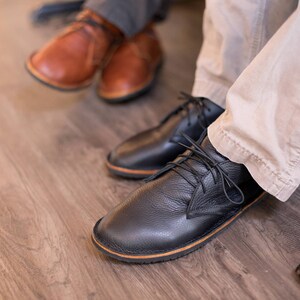 Puede incluir: Dos pares de zapatos de cuero. Un par es marr&oacute;n y el otro par es negro. Los zapatos negros tienen cordones.